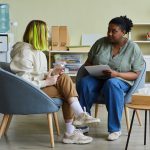 Woman social worker talking to teenage girl at office