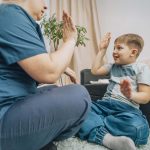 speech therapist engaging with young boy in nonverbal communication training, living room with warm decor, concept of education and cognitive skills development